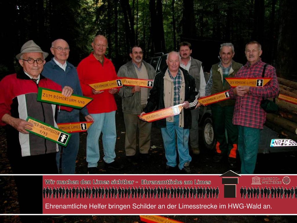 Ehrenamtliche Helfer bringen Schilder an der Limesstrecke im HWG-Wald an.