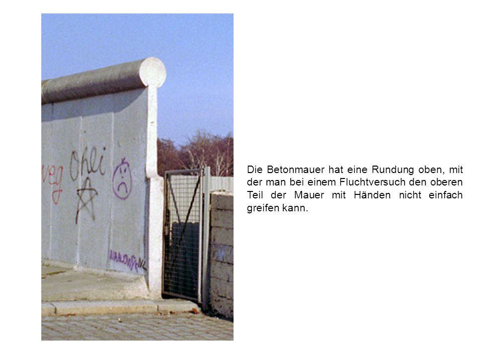 Die Betonmauer hat eine Rundung oben, mit der man bei einem Fluchtversuch den oberen Teil der Mauer mit Händen nicht einfach greifen kann.